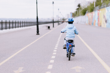 A child in a helmet and protection in a bike ride on nature in the spring