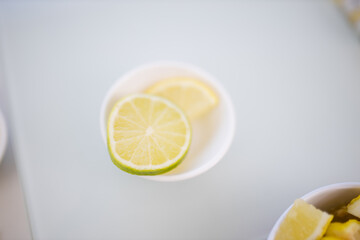 Lime and lemon slices in a small bowl above white table