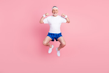 Full length body size photo senior man jumping in gym showing strong biceps isolated pastel pink...