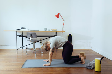 Frau macht Yoga im Homeoffie zur Entspannung und als Ausgleich 