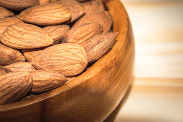Peeled almond in a wooden bowl on wooden plank.