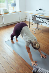 Frau macht Yoga im Homeoffie zur Entspannung und als Ausgleich 