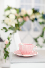 Elegant vintage cup on background of terrace overgrown with flowers. Spring pretty background. Spring and Easter mood. Shabby chic style. Morning tea ceremony. Tender beautiful decor