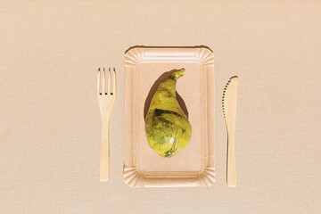 Pear wrapped in polyethylene plastic on the beige paper background. Immature, tasteless or inedible...