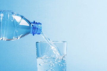 Pour fresh, clean water from a plastic bottle into a glass beaker.