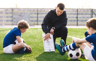 Young Soccer Coach Explaining to Kids Tactics Details. Children on Football Training. School Boys...