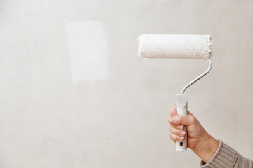 Painting roller in worker's hand. Repair in a room. Painting of walls