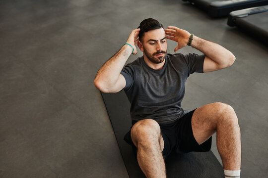 Black hair, bearded muscular man doing abs core crunch sit up exercise