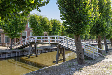 Fototapeta na wymiar A wooden white bridge over the canal in the picturesque town of Sloten in the Netherlands