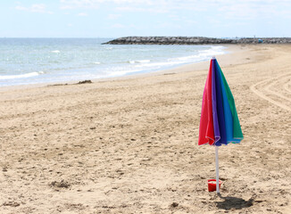 isolated umbrella in the middle of the beach with no person and the sea