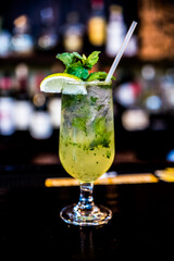 Mojito cocktail with lime on the rim of the glass is placed on the counter bar in the restaurant.