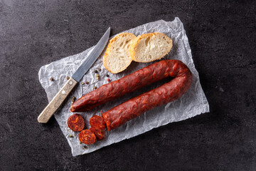 Spanish chorizo sausage and bread on black stone. Top view