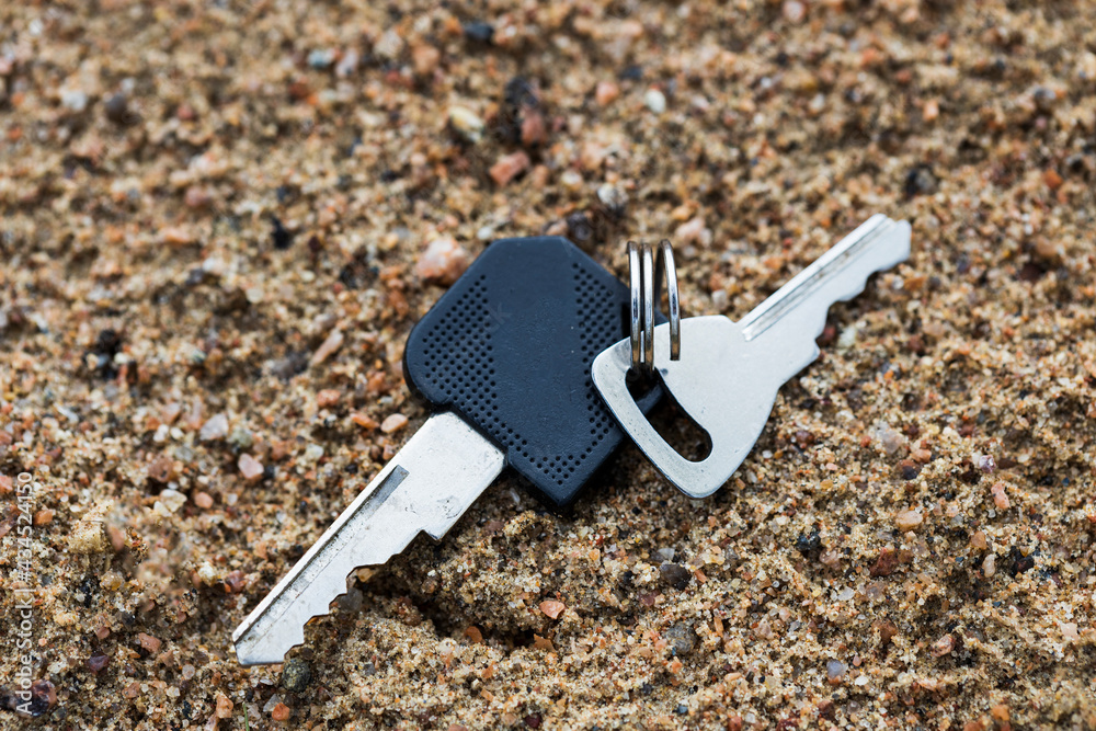 Poster two keys lie on the sand. loss of the keys to the house