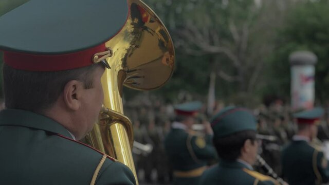 A military brass band plays a musical instrument during a city holiday