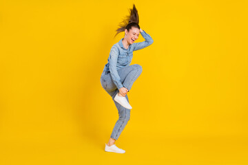 Fototapeta na wymiar Full size photo of attractive young positive lady fly hair funky funny mood hold hands leg isolated on yellow color background