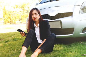 Businesswoman sitting in front of the car, parked on the grass in a place that was unfamiliar with...