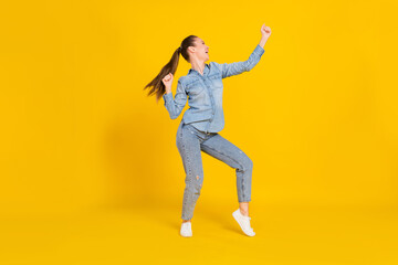 Fototapeta na wymiar Full length photo of funky adorable young lady dressed jeans shirt dancing smiling isolated yellow color background