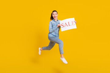 Full length body size photo smiling girl jumping up running keeping sale table isolated vivid yellow color background