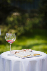 Bible, vine and wedding rings on a table in a garden. Reading outdoor. Relax on air. Poetic. Wedding ceremony outdoor. Wedding ceremony decoration in the garden.