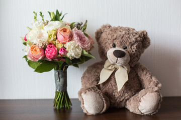 delicate wedding bouquet on brown surface near cute bear toy