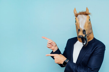 Man with horse mask pointing to the side.Copy space.