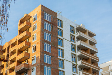 Fototapeta premium construction of brick house multi-storey residential building. crane build multi-storey residential house. Modern residential construction. Residential fund