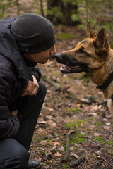 Man with dog nose to nose in the autumn forest. A loyal and friendly relationship between man and dog