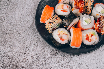 Sushi bar lunch menu. Top view of sushi rolls with salmon, avocado and smocked eel on the concrete table background - futomaki. uramaki, hosomaki. Order food online and home delivery food concept