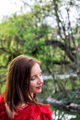 brunette young woman in red dress in nature looking over her shoulder