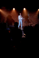 Black African American young female comedian performing her stand-up monologue on a stage of a...