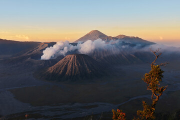 Active volcano in clouds of smoke with crater in depth. Sunrise behind Mount Gunung Bromo volcano in East Java, Indonesia.