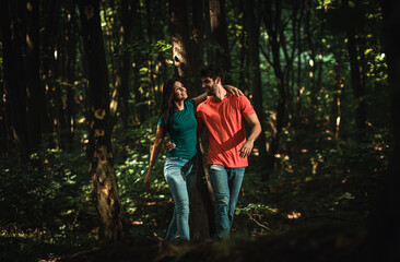 Young couple enjoys together walking through the forest.