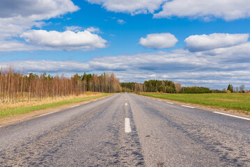 Fototapeta na wymiar Asphalt road field and forest sunny white cloud blue sky shot.