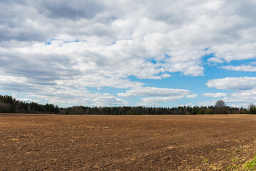 Agricultural rural background early spring landscape.white clouds blue sky over the forest in the background.