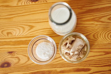 Top view of fresh yeast dough starter ingredients concept: milk, sugar and fresh wild yeast in transparent glasses on wooden table background. High quality photo