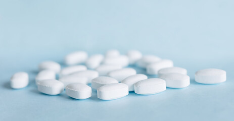 White pills on a light blue background. Healthcare and medicine.