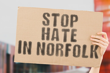 The phrase " Stop Hate in Norfolk " on a banner in men's hand. Human holds a cardboard with an inscription. Communication. Equality. Society. Community. Civi rights. Verbal abuse. Sex. United Kingdom