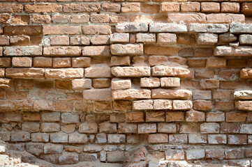 Ruins of an ancient castle. Destroyed brick walls with loopholes. History of ancient architecture. Brick old background