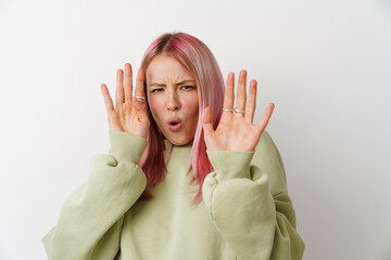 Young displeased woman with pink hair showing stop gesture at camera