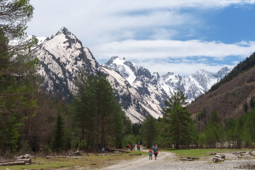 Obraz premium tourists are walking along the road against the background of a large snow-capped mountain