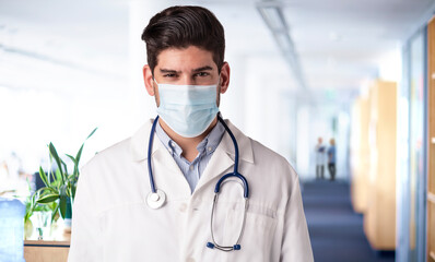 Male doctor portrait while wearing face mask on the hospital's foyer