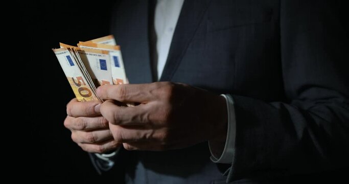 white collar crime - businessman counting euro banknotes on dark background. shadow economy money laundering and corruption concept
