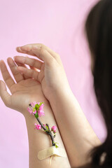 Female hands with pink flower on a branch