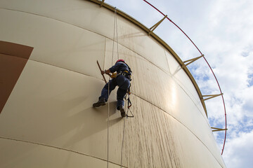 Male worker rope access height safety inspection of thickness storage oil and gas tank