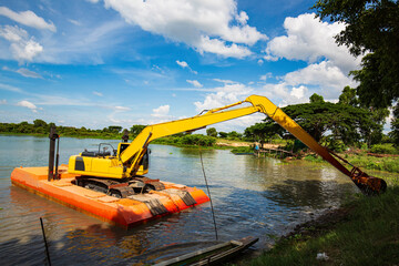 The yellow backhoe is working at the river floatin