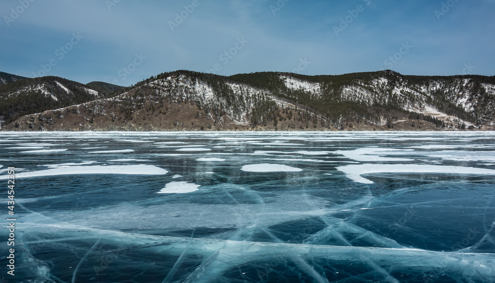 Wall mural deep intersecting cracks are visible on the frozen lake. plots of snow on the surface of blue ice. o