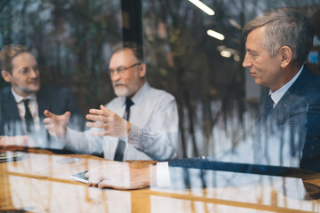 Group of male colleagues talking while sitting together at table