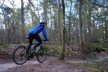 Naklejka premium man exercises on mountain bike in spring forest near utrecht in holland