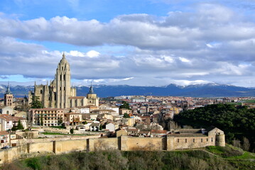 Naklejka premium View from the castle to the old city. Backdrop of snow capped mountains and voluminous clouds. Ancient architecture of Segovia, Castile and Leon region, Spain 