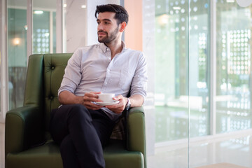 Portrait of handsome man drinking coffee at hotel lobby.